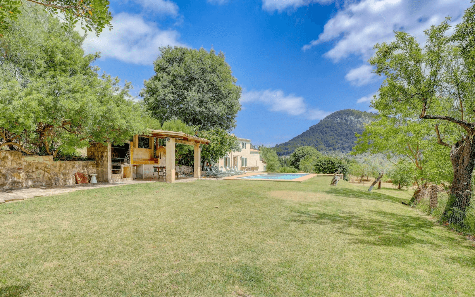 Backyard with a swimming pool, outdoor kitchen, and house overlooking a scenic mountain landscape.